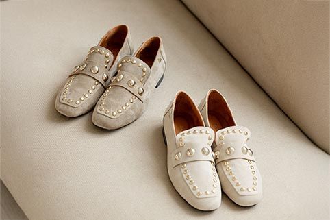 2 paar lichte mocassins op een beige bank