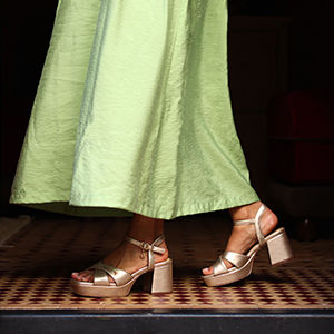 Model met groene lange jurk en feestelijke sandalen met hak