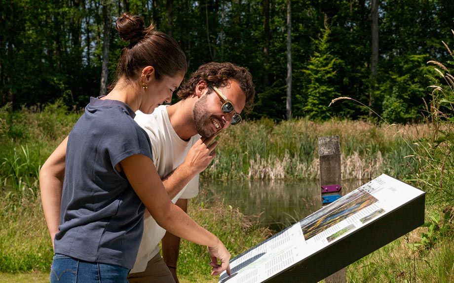 Man en vrouw kijken op informatiebord in groene omgeving