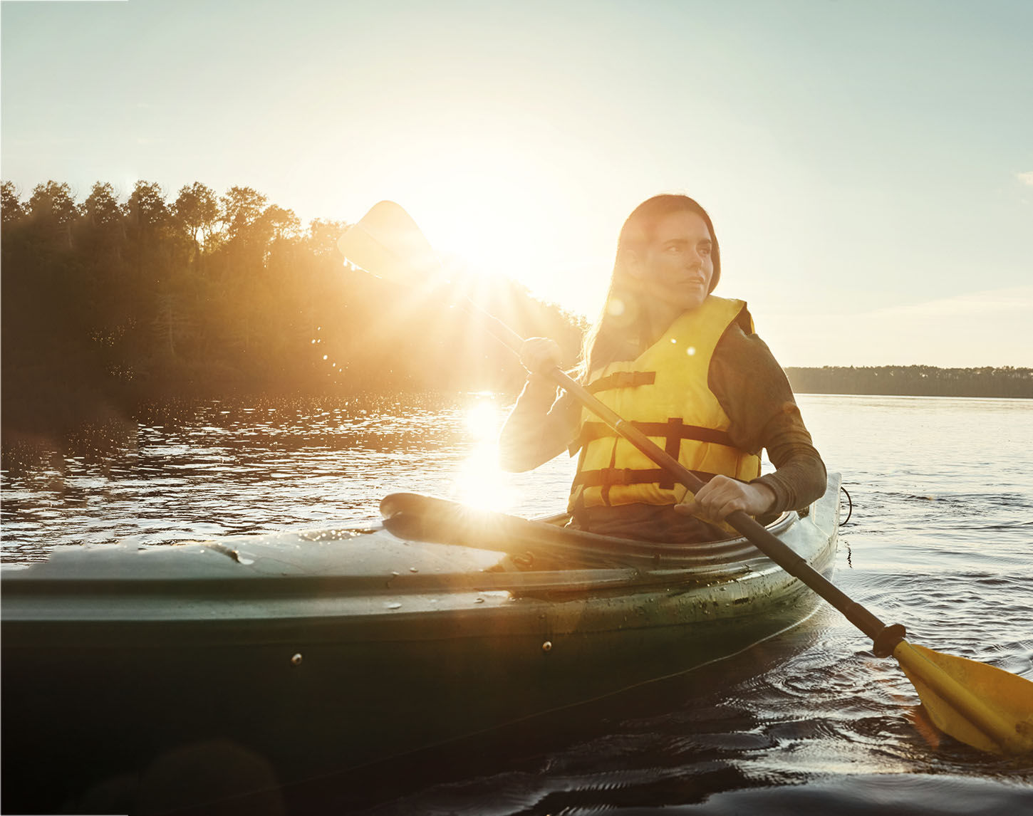 Vrouw met lifejacket tijdens kanotocht bij ondergaande zon