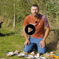 Man in natuurgebied met materiaal voor vuur maken