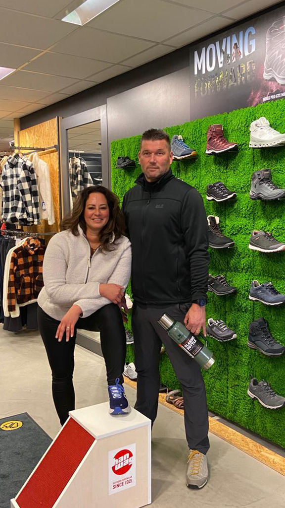 Man en vrouw voor schoenenwand en kledingrekken op achtergrond